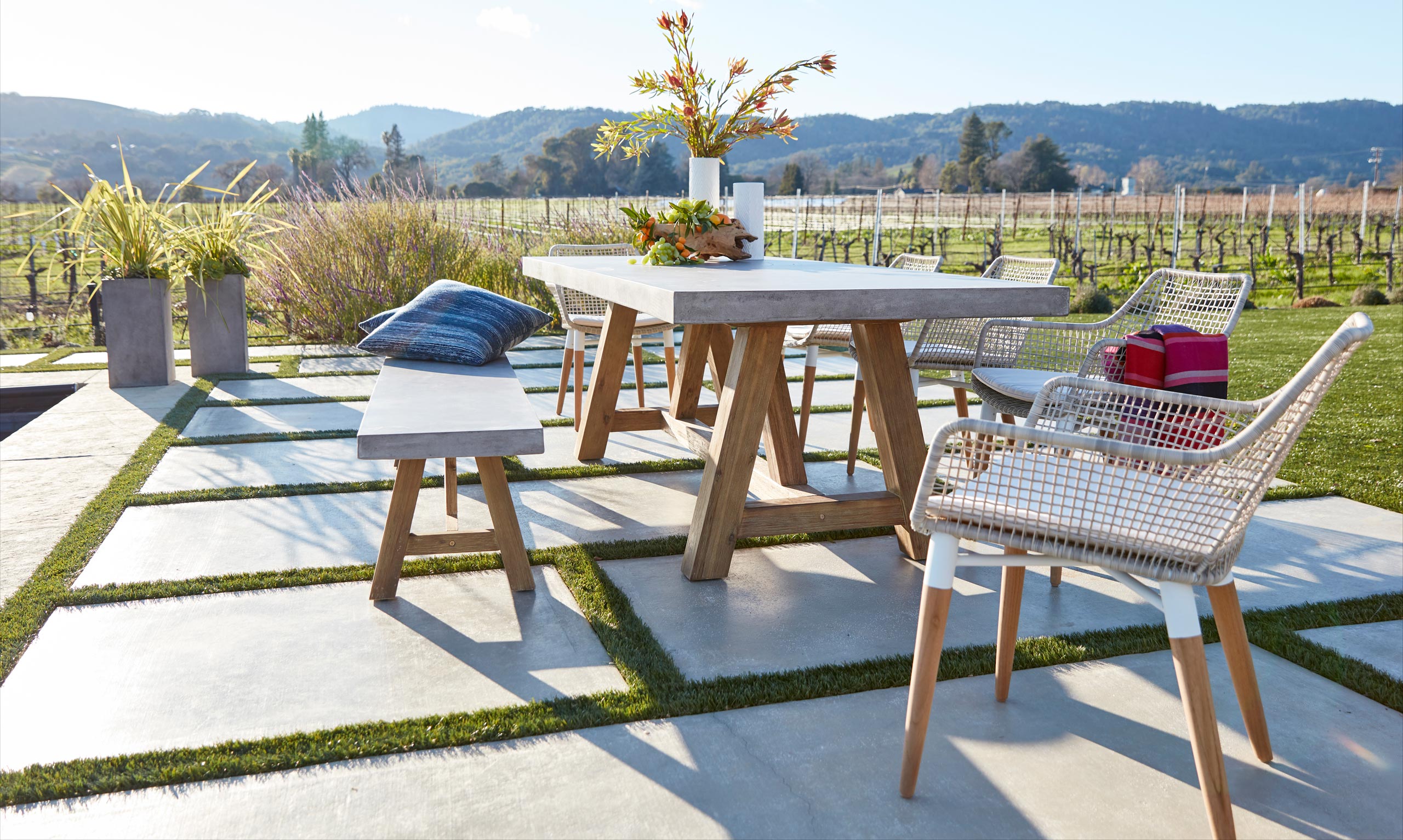 Concrete outdoor dining table and benches paired with stylish dining chairs