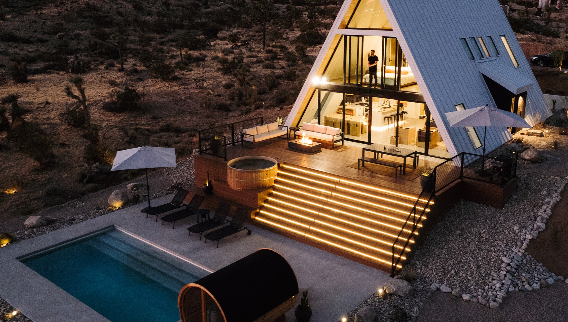 A-frame house with pool and outdoor furniture at night