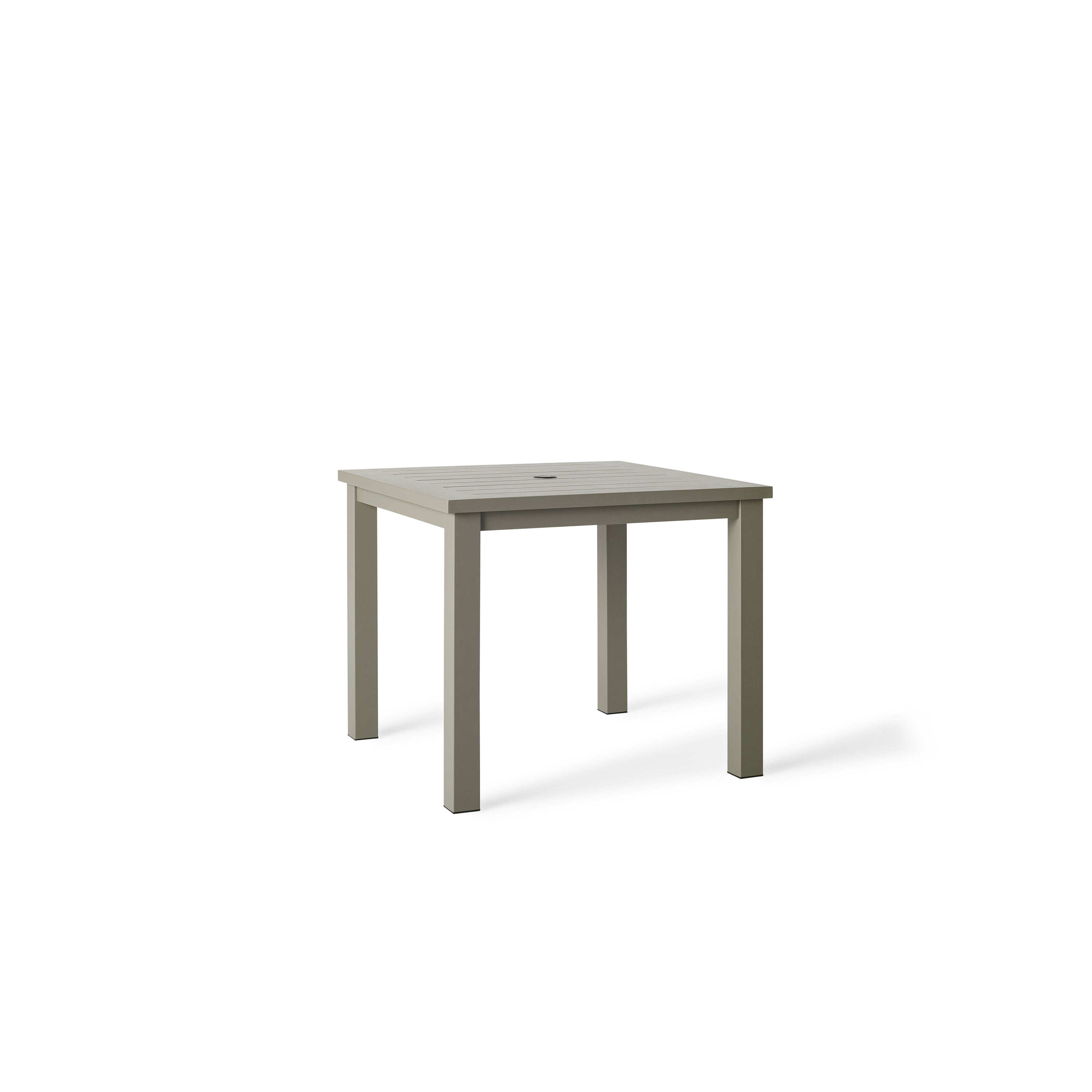 Belvedere Square Dining Table by Terra Outdoor Living in Quartz Grey, a warm grey tone, shown with a slatted aluminum top and central umbrella hole, featuring a clean-lined, modern silhouette in a compact size for versatile outdoor placement.