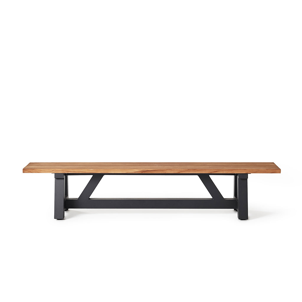 Madera Bench with Golden Teak Top by Terra Outdoor Living has a charcoal colored aluminum trestle base, topped with planks of premium teak in a natural 'golden' finish. Also available with a white colored base.