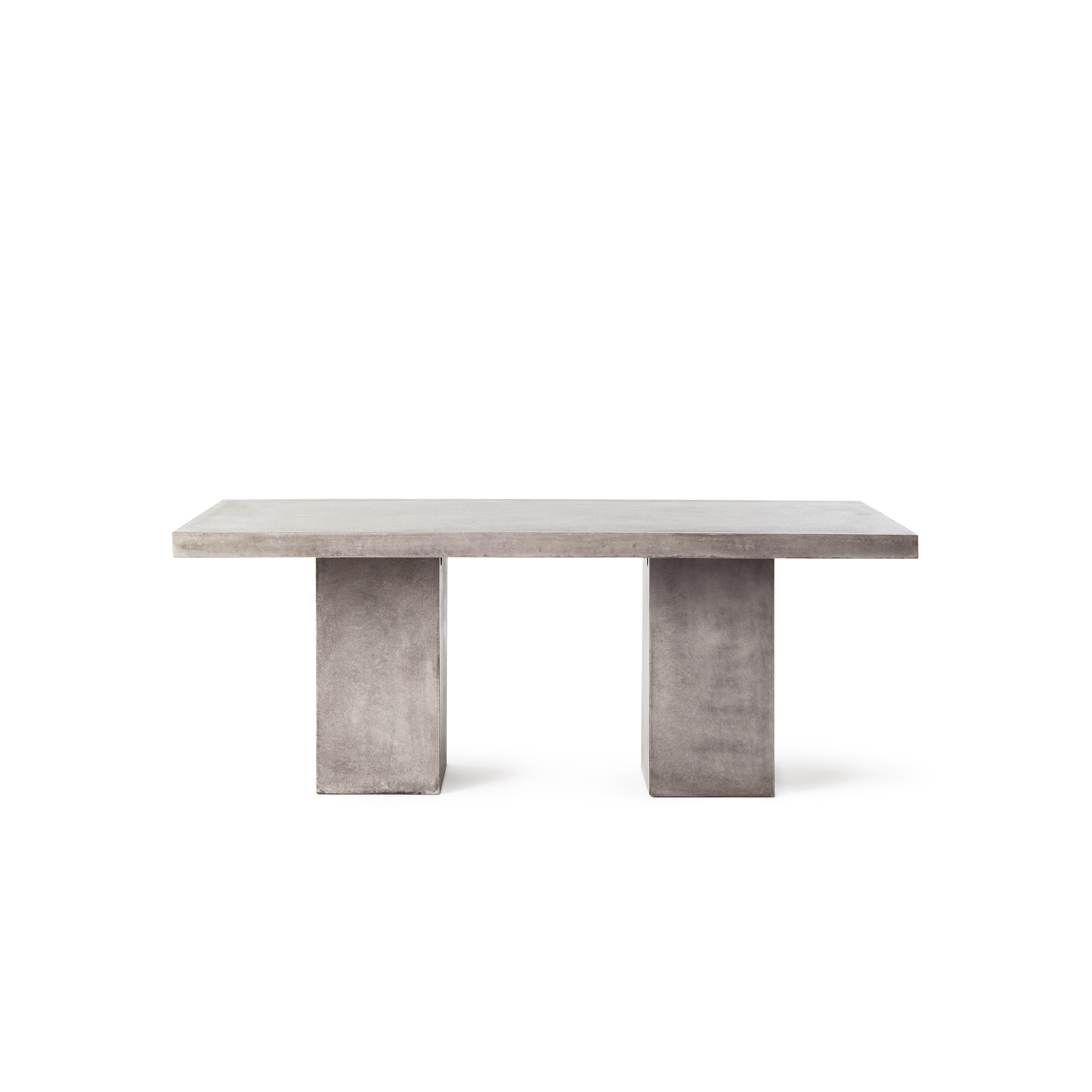 Mason 79" Dining Table by Terra Outdoor Living is made entirely of Glass Fiber Reinforced Concrete (GFRC), which resembles the look and feel of concrete but at a fraction of the weight and with increased strength. It features two cuboid bases as legs, with a slab of thick-edged GFRC as the top.