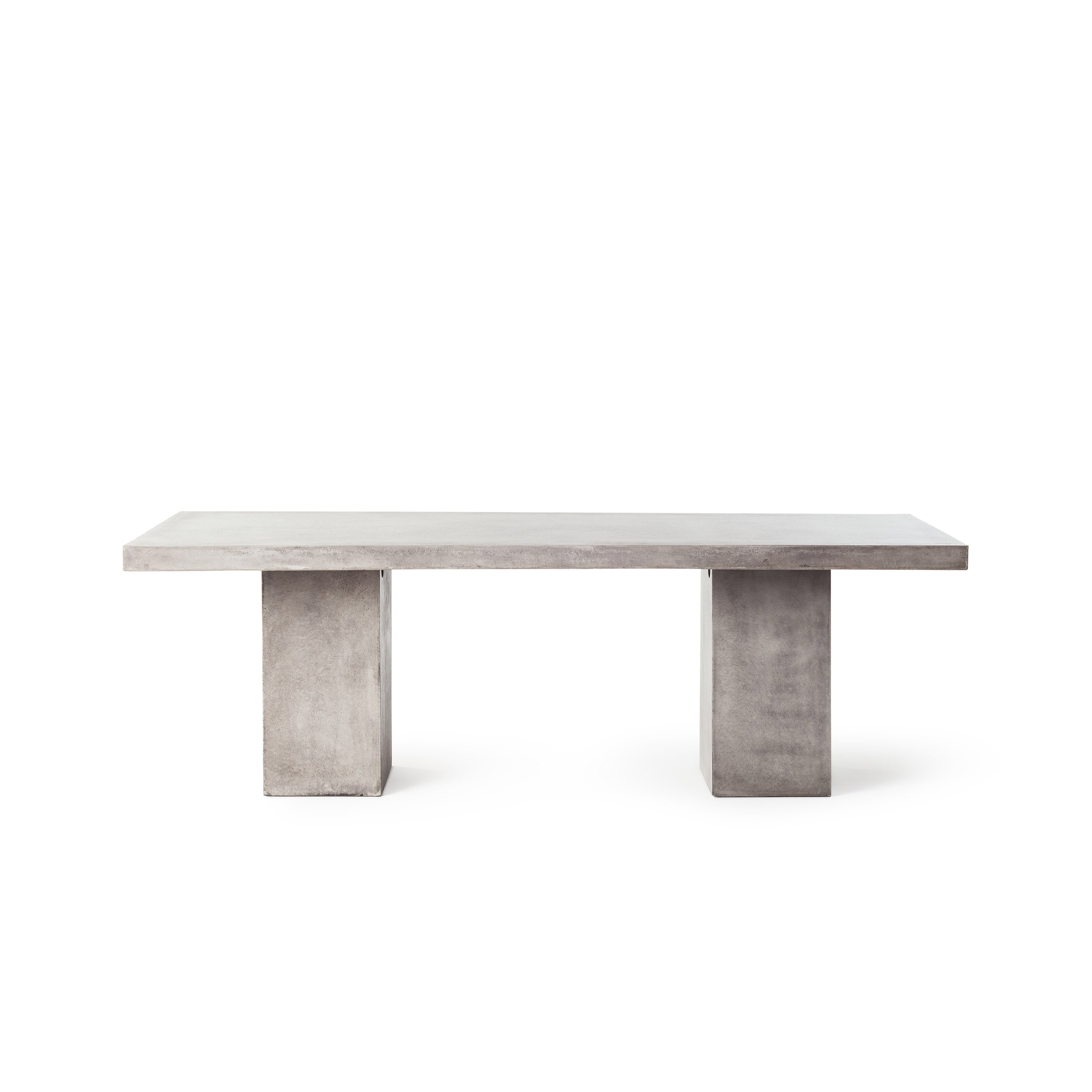 Mason 95" Dining Table by Terra Outdoor Living is made entirely of Glass Fiber Reinforced Concrete (GFRC), which resembles the look and feel of concrete but at a fraction of the weight and with increased strength. It features two cuboid bases as legs, with a slab of thick-edged GFRC as the top.