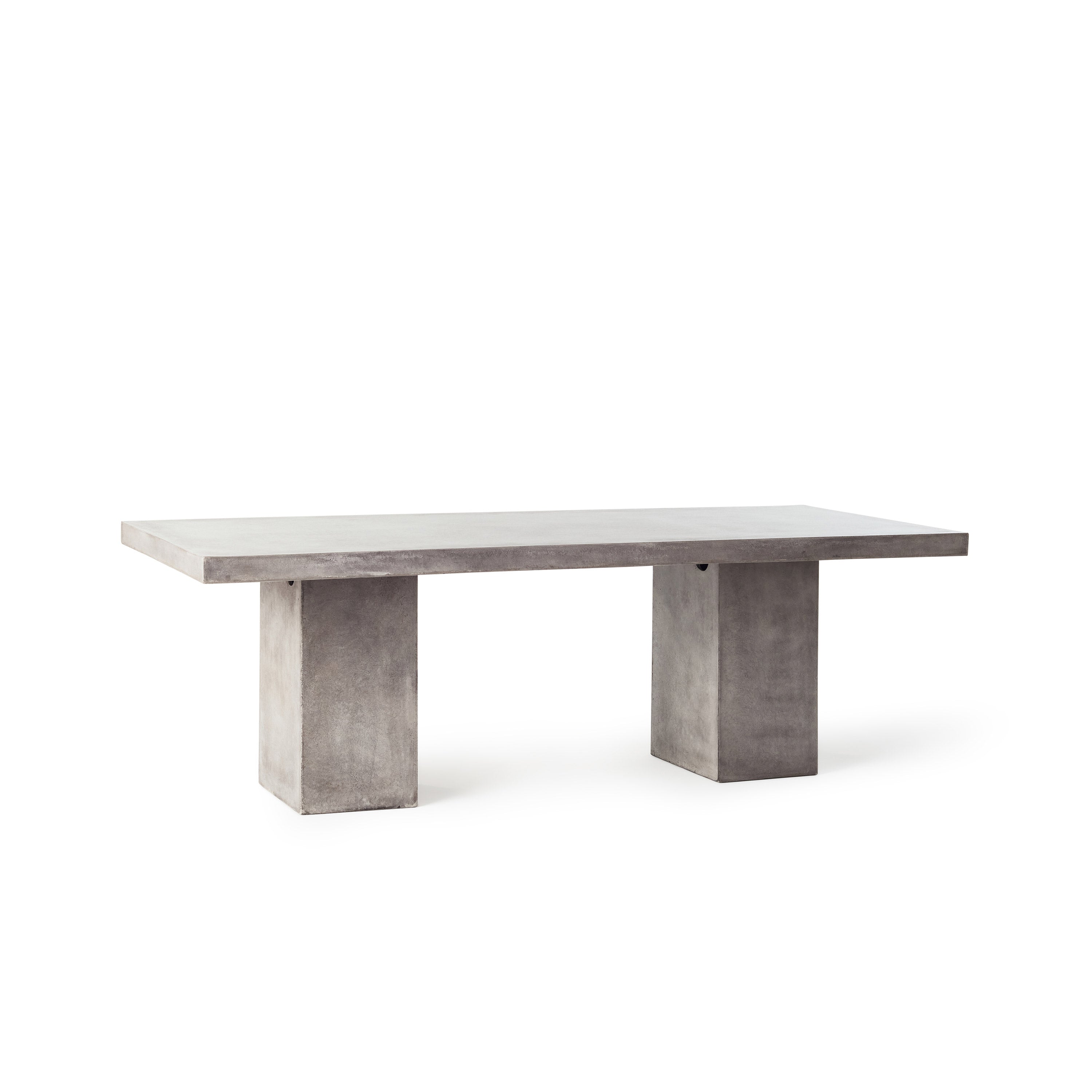 Mason 95" Dining Table by Terra Outdoor Living is made entirely of Glass Fiber Reinforced Concrete (GFRC), which resembles the look and feel of concrete but at a fraction of the weight and with increased strength. It features two cuboid bases as legs, with a slab of thick-edged GFRC as the top.