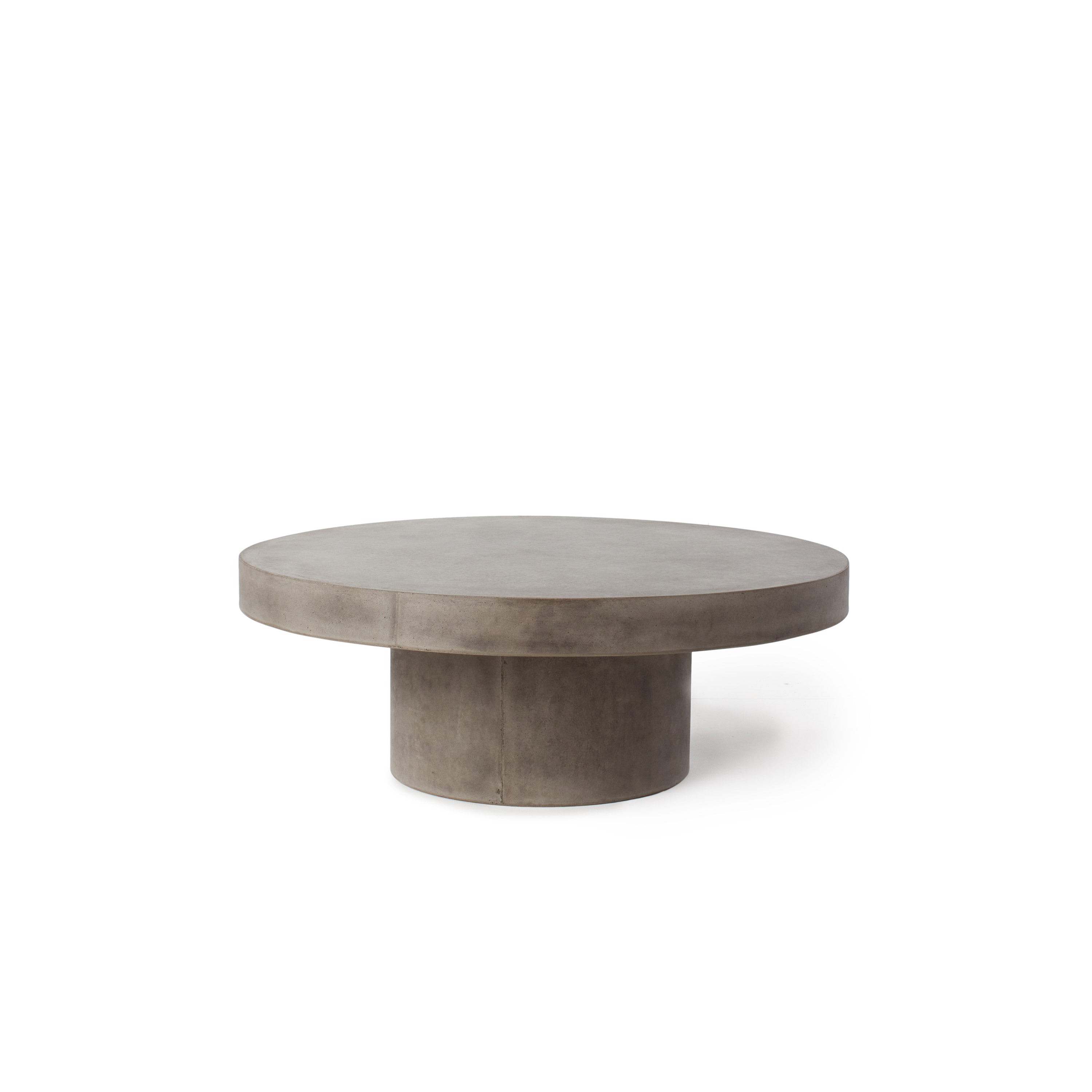 Mason Floating Round Coffee Table by Terra Outdoor Living is made entirely from Glass Fiber Reinforced Concrete (GFRC) - its surface effect resembles that of industrial concrete. It features a cylindrical pedestal base, and a thick-edged round slab of GFRC as the top.