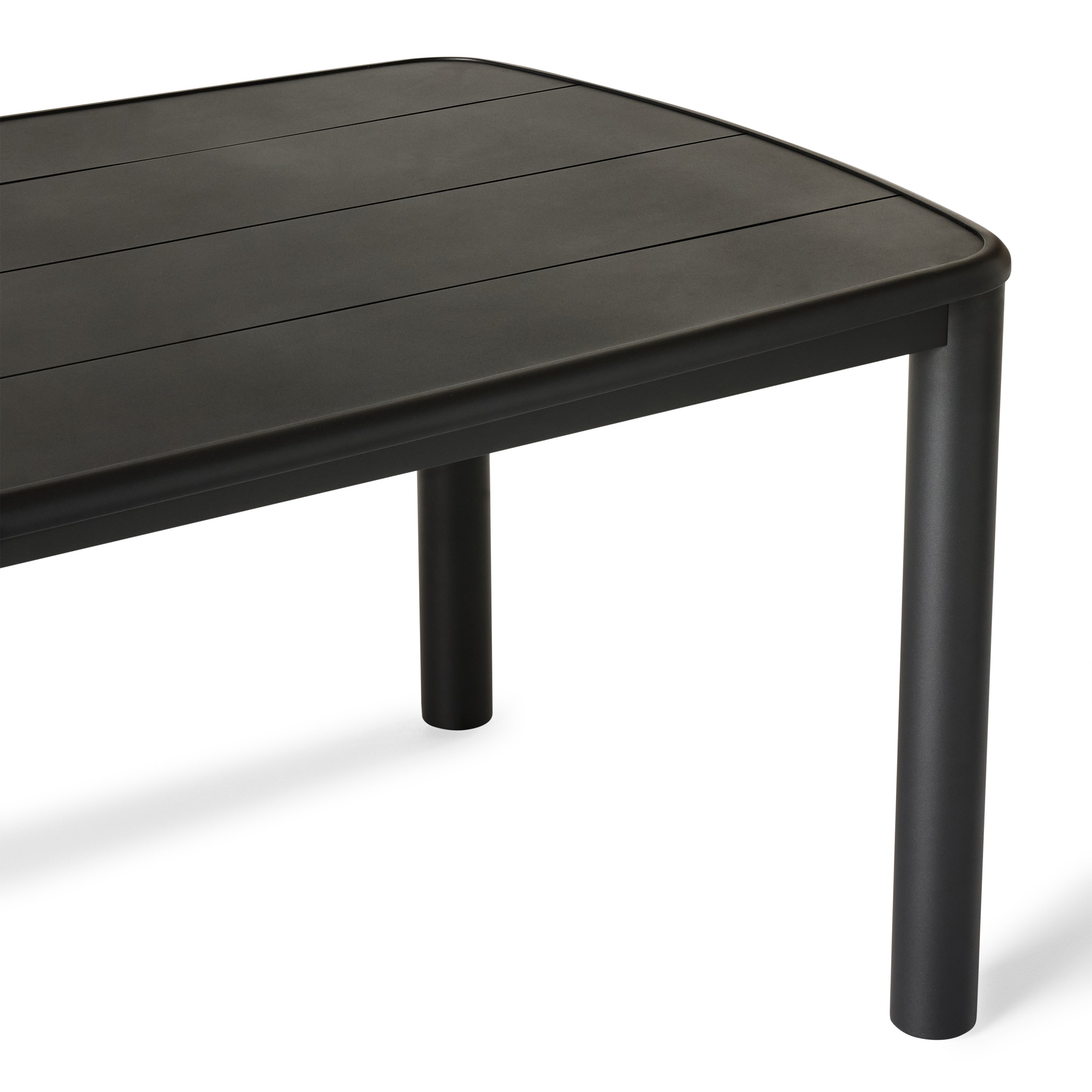 A close up of Stinson Dining Table in Aluminum by Terra Outdoor Living — crafted with a powdercoated aluminum frame in a charcoal finish, featuring a spacious slatted top that allows water to drain; comfortably seats up to 8 people, ideal for pairing with Stinson Dining Chairs or any of our dining chairs.