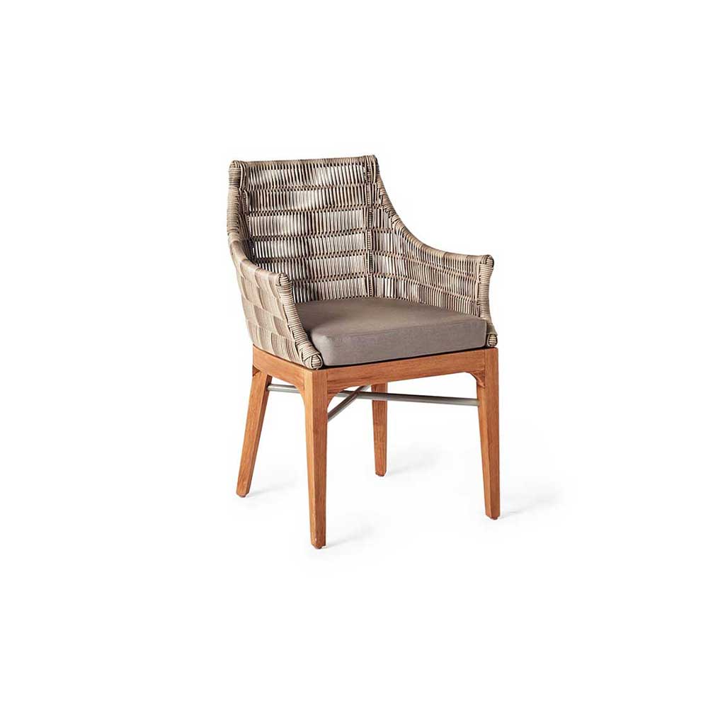 The Madera Dining Chair in Teak and All-Weather Wicker by Terra Outdoor Living has four legs made of solid premium teak, reinforced by metal crossbars. The arms and seat-back are made from a tightly woven all-weather wicker. For comfort, there is a thick, quick-drying cushion wrapped in Sunbrella fabric.