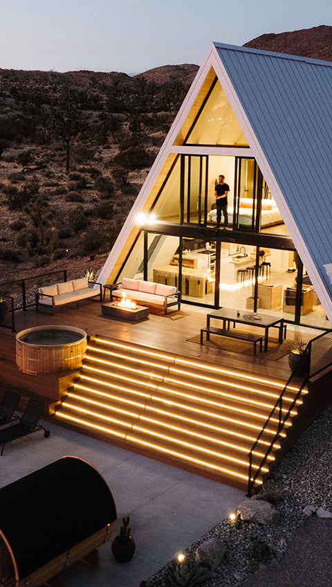 A-frame house with pool and outdoor furniture at night