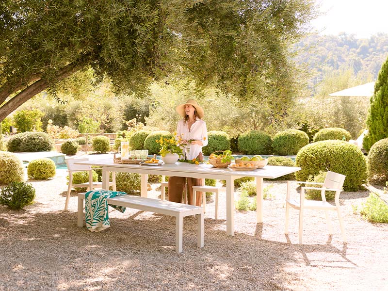 Woman standing by a table outdoors with greenery and mountains in the background