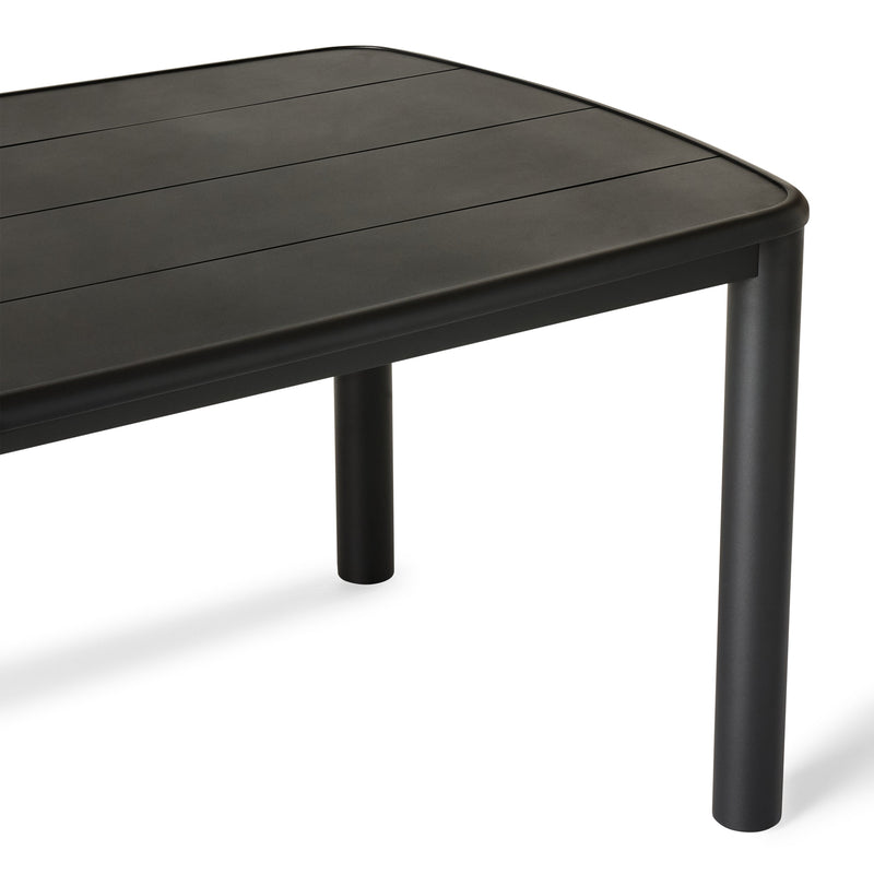 A close up of Stinson Dining Table in Aluminum by Terra Outdoor Living — crafted with a powdercoated aluminum frame in a charcoal finish, featuring a spacious slatted top that allows water to drain; comfortably seats up to 8 people, ideal for pairing with Stinson Dining Chairs or any of our dining chairs.